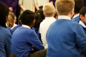 Young primary school aged children sit in a school assembly