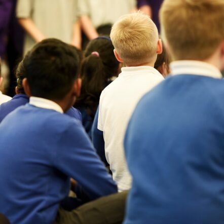 Young primary school aged children sit in a school assembly