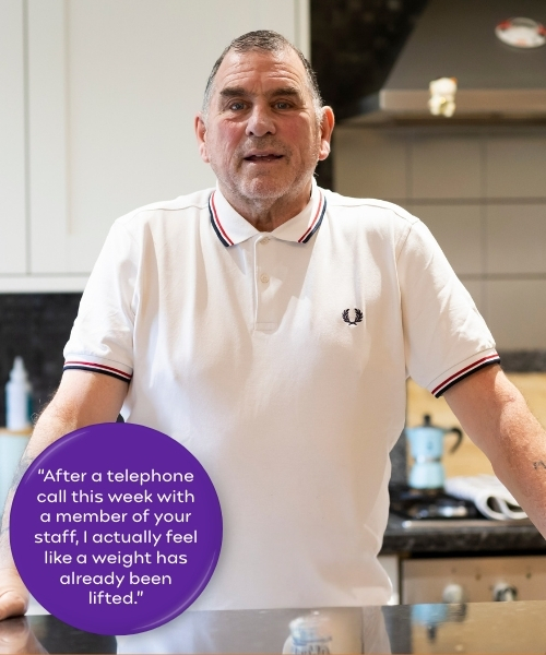 Carer support. Man standing in kitchen wearing white polo shirt. Quote in purple circle reads, "After a telephone call this week with a member of your staff, I actually feel like a weight has already been lifted.”