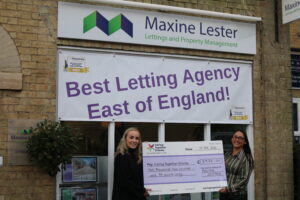 Two members of staff from Maxine Lester letting agency holding a cheque for almost £3,000 for Caring Together Charity.