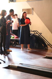 Children's Commissioner for England, Dame Rachel de Souza, holding a bowling ball as two young carers look on