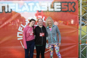 Thalia, Keola and mum Jo stood in front of an Inflatable 5K banner.